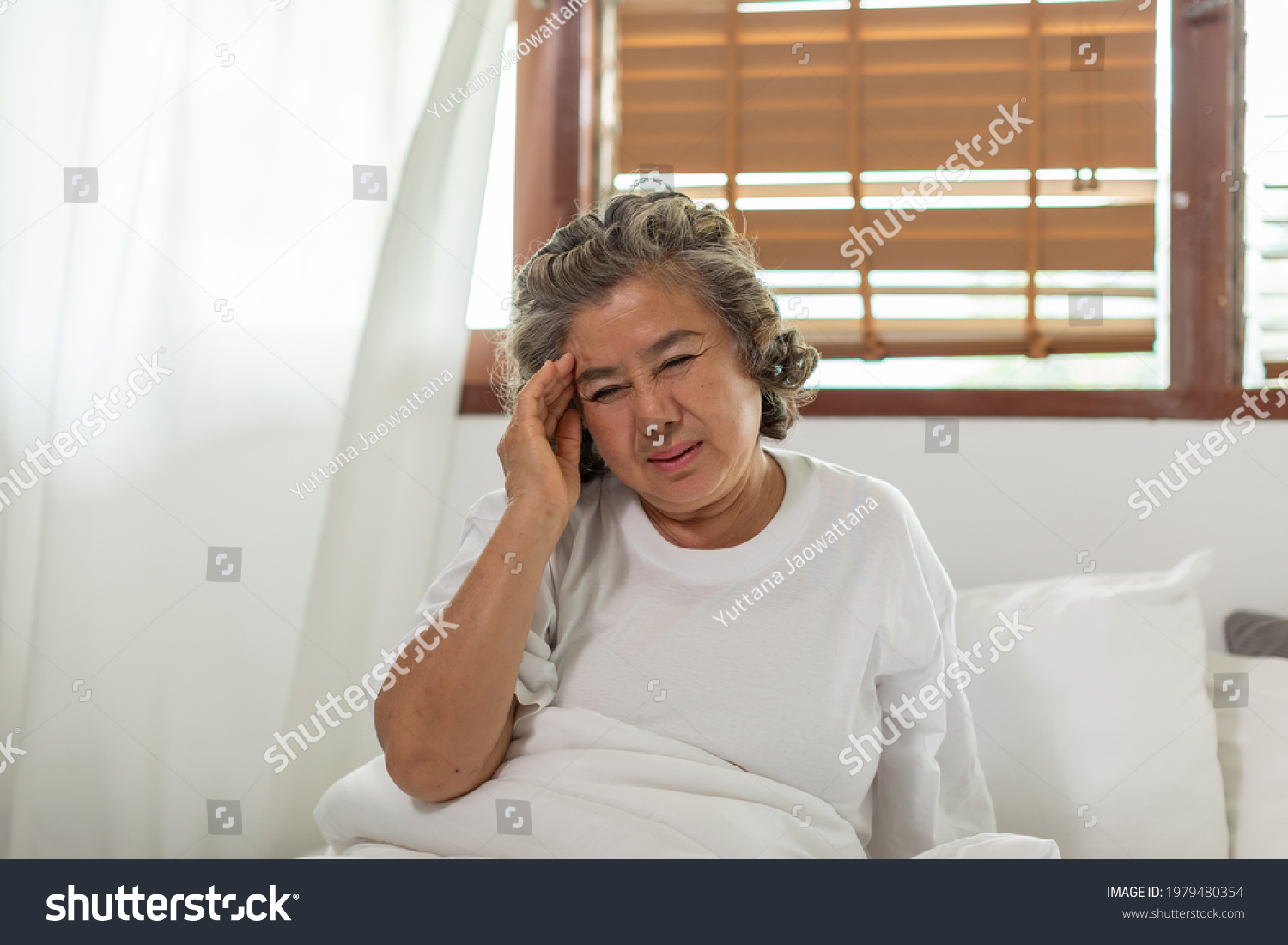Asian Elderly senior woman sudden headache and migraine so pain and illness on bed alone at home Elderly Care Concept