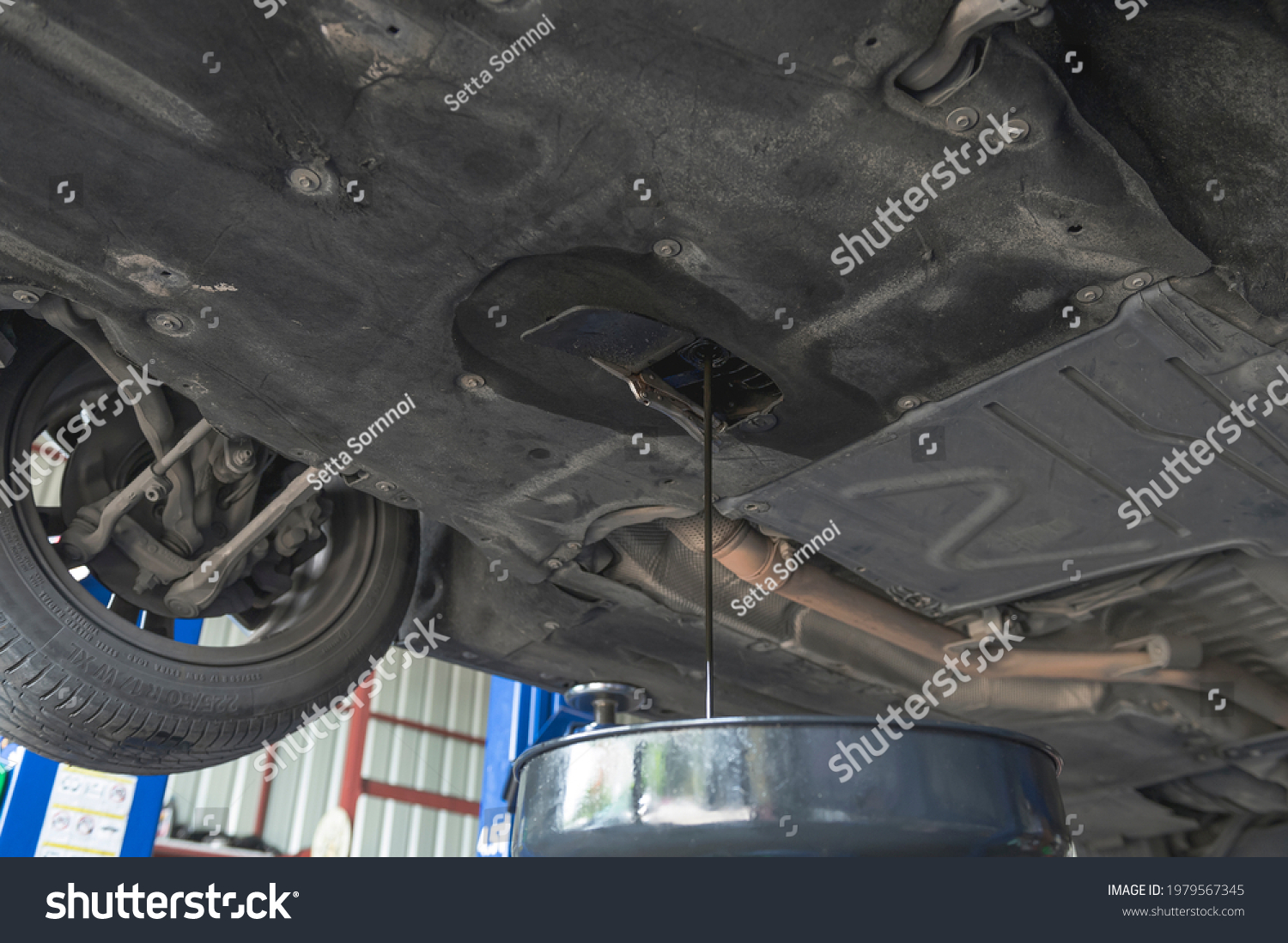 Auto mechanic loosen the oil drain plug then let the dirty used engine