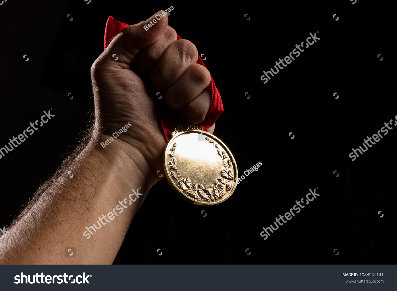 hand holding a gold medal on black with blank face for text  concept for winning or success