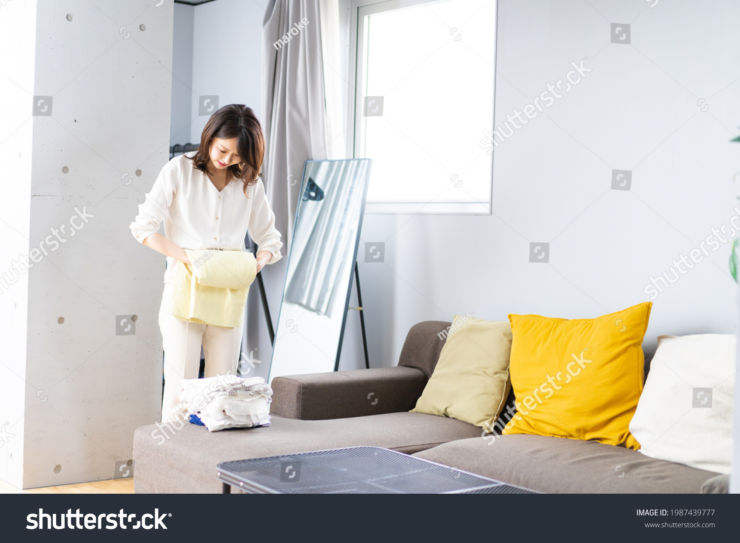 A young woman folding laundry at home