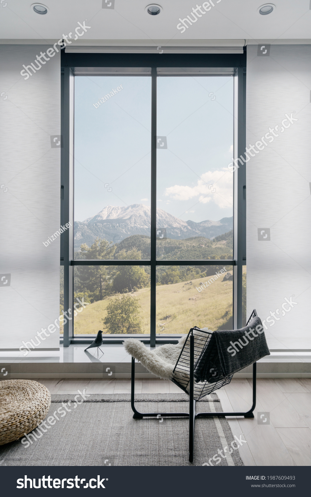 Vertical shot of modern metal chair on gray carpeted floor in front of large window with amazing mountain landscape in light coloured living room. Minimalist interior design in hotel room or house