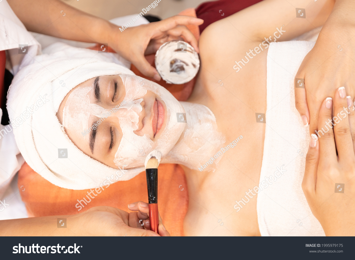 young woman with facial mask at beauty spa salon