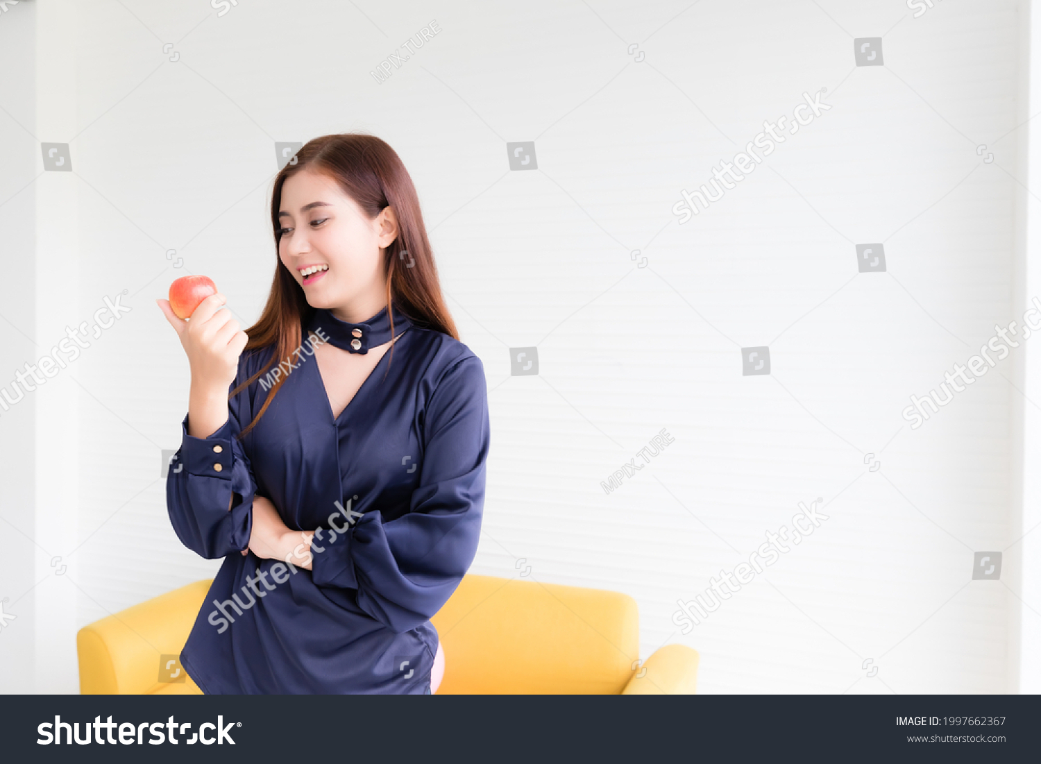 Beautiful Asian woman in casual clothes picking up and looking at an apple