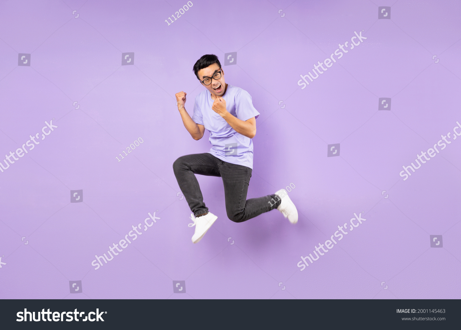 Portrait of a jumping asian man  isolated on purple background
