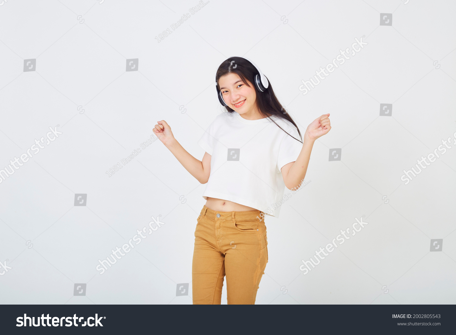 Young Asian woman with headphones and dancing on white background