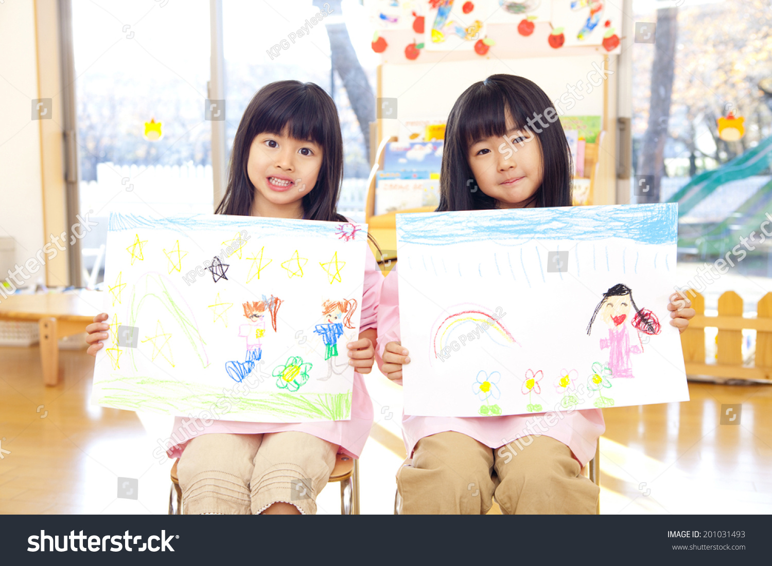 two smiling kindergarten girls with a picture