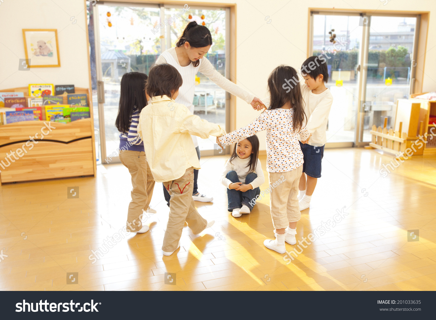 children and a nursery teacher dancing in a circle