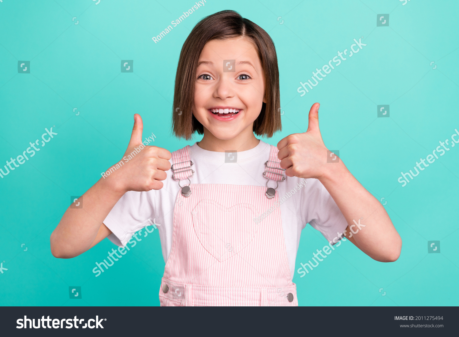 Photo of cheerful happy young small girl make fingers thumbs up smile recommend isolated on teal color background