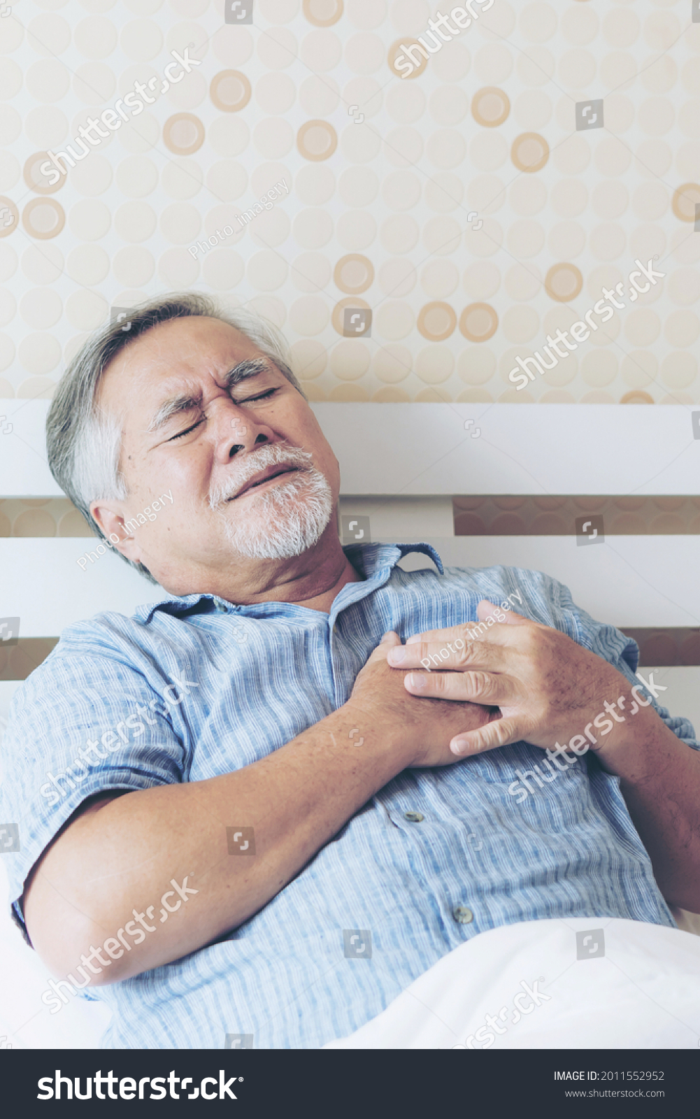 Senior Asian man  suffering from bad pain in his chest heart attack at home - senior heart disease concept