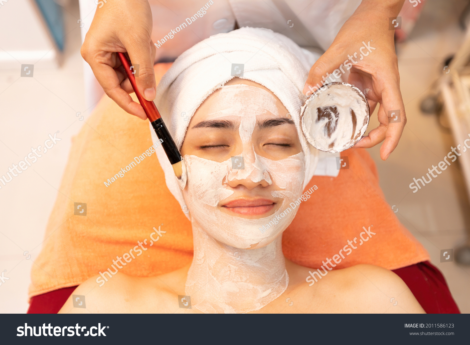 young woman with facial mask at beauty spa salon