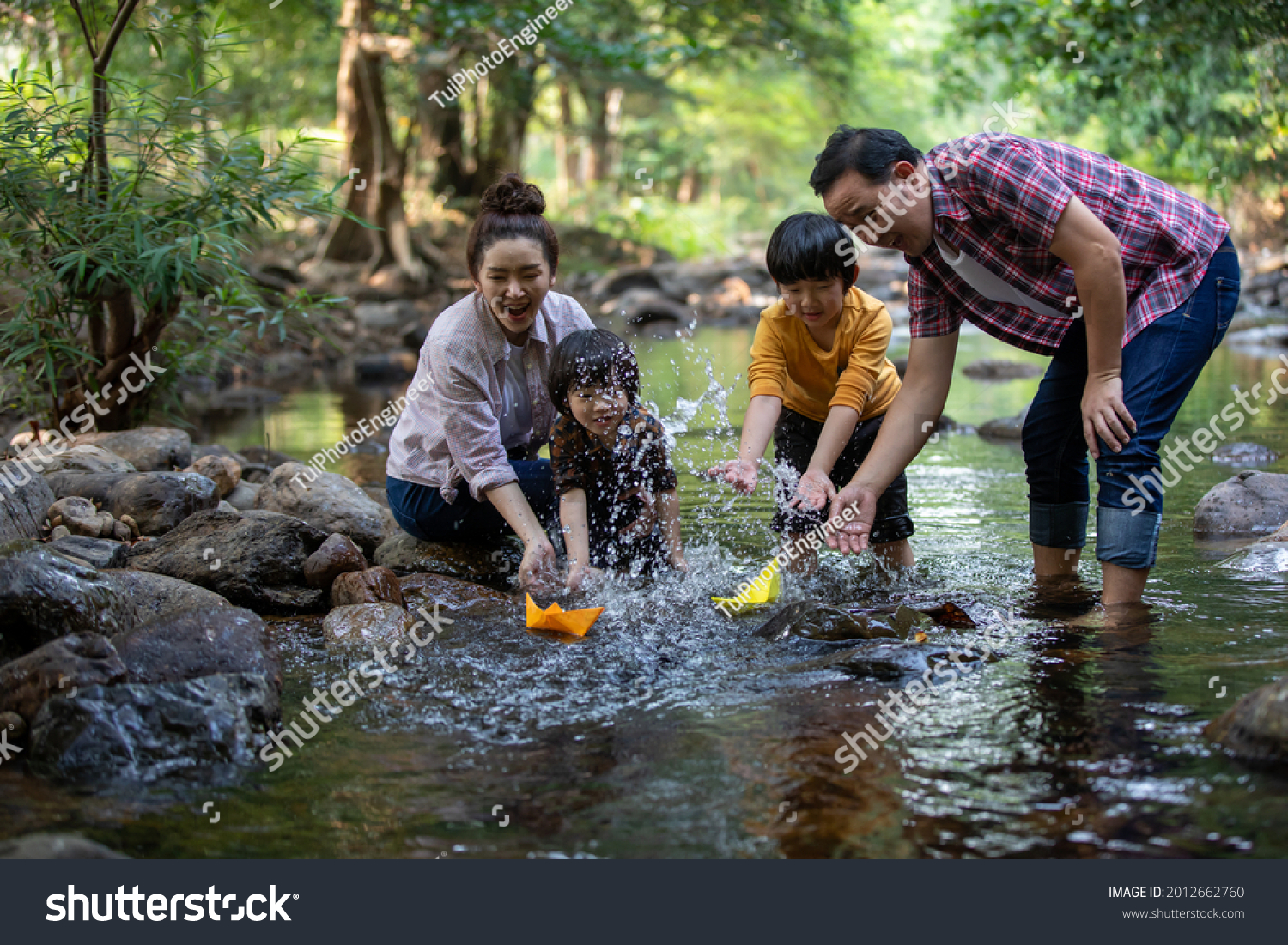Two son playing with paper boats at river  Asian family happy