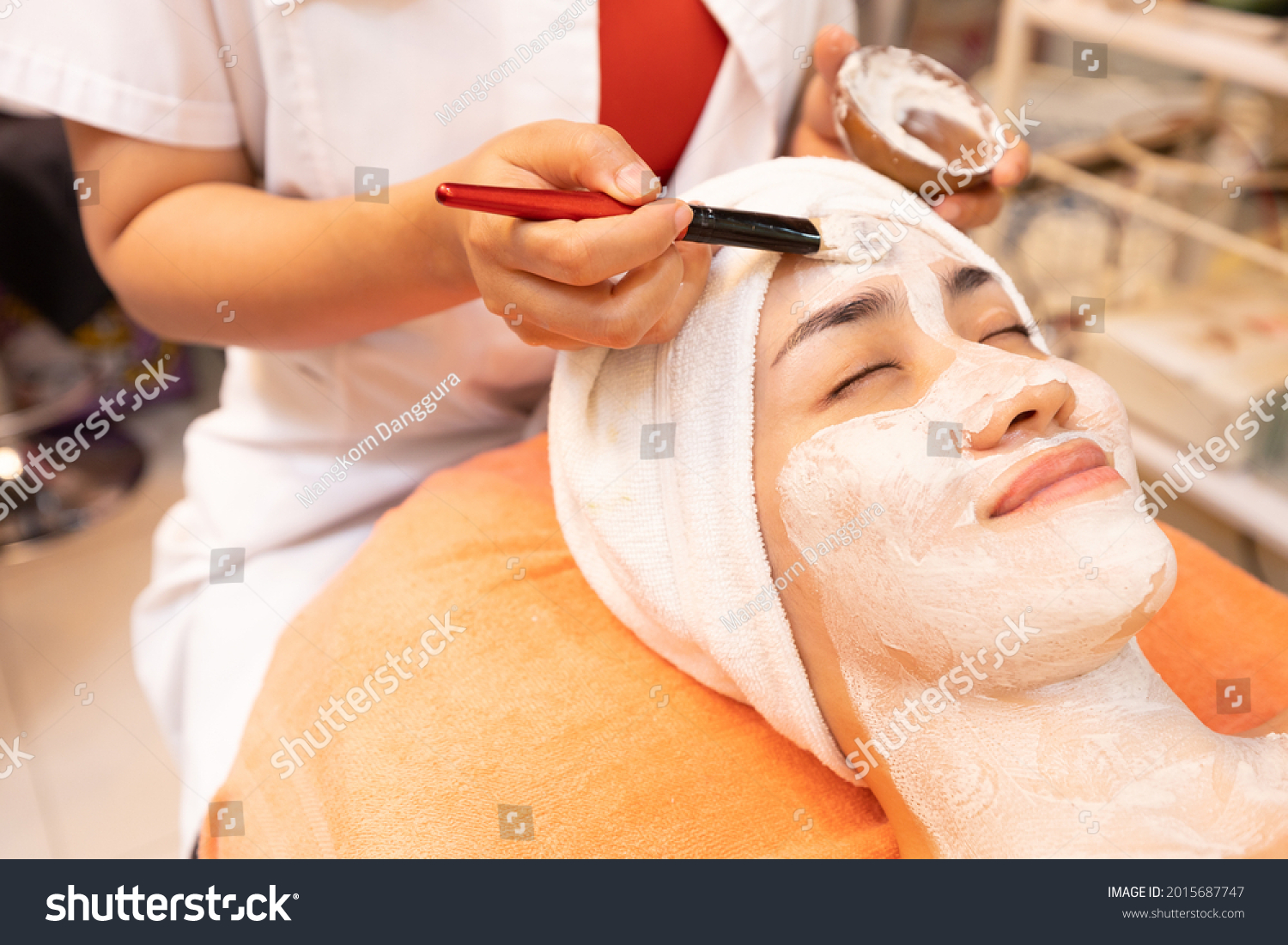 young woman with facial mask at beauty spa salon