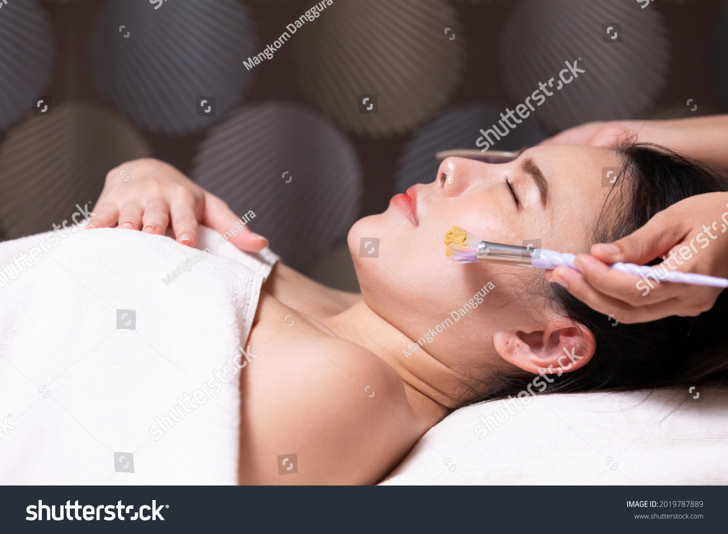 young woman with facial mask at beauty spa salon