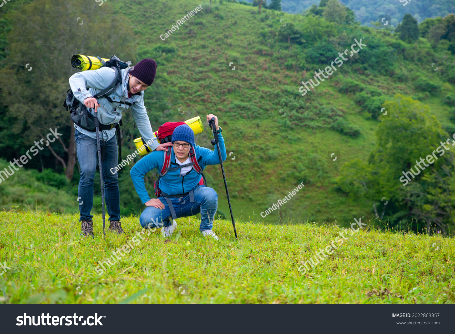 Two handsome Asian man friends backpacker with backpack hiking together on mountain trail. Healthy male friendship enjoy outdoor activity and active lifestyle climbing and camping in summer vacation.