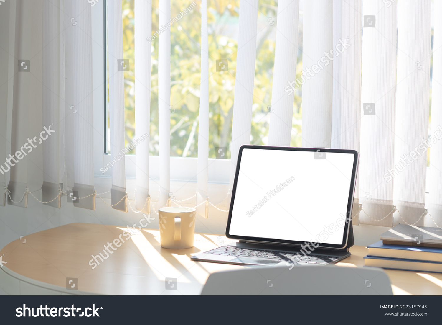 Laptop computer or tablet with white blank screen on wood desk