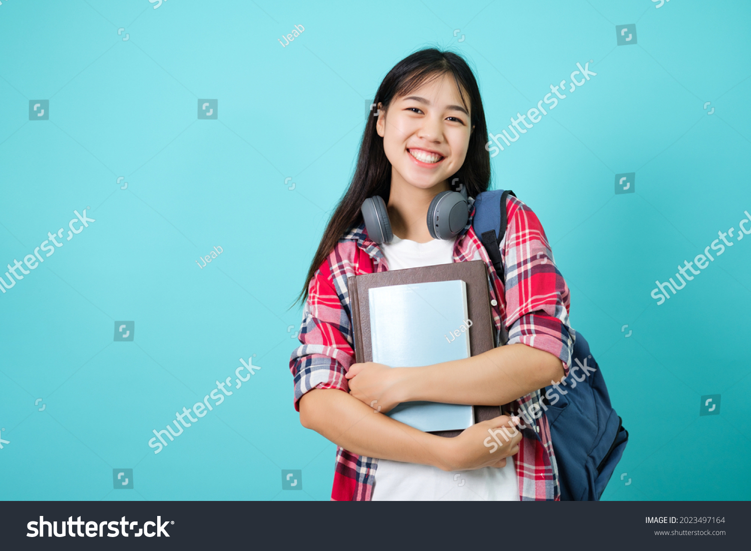 Happy Student. Cheerful Asian Girl Smiling To Camera Standing With Backpack In Studio Over Blue Background. Back to school concept.