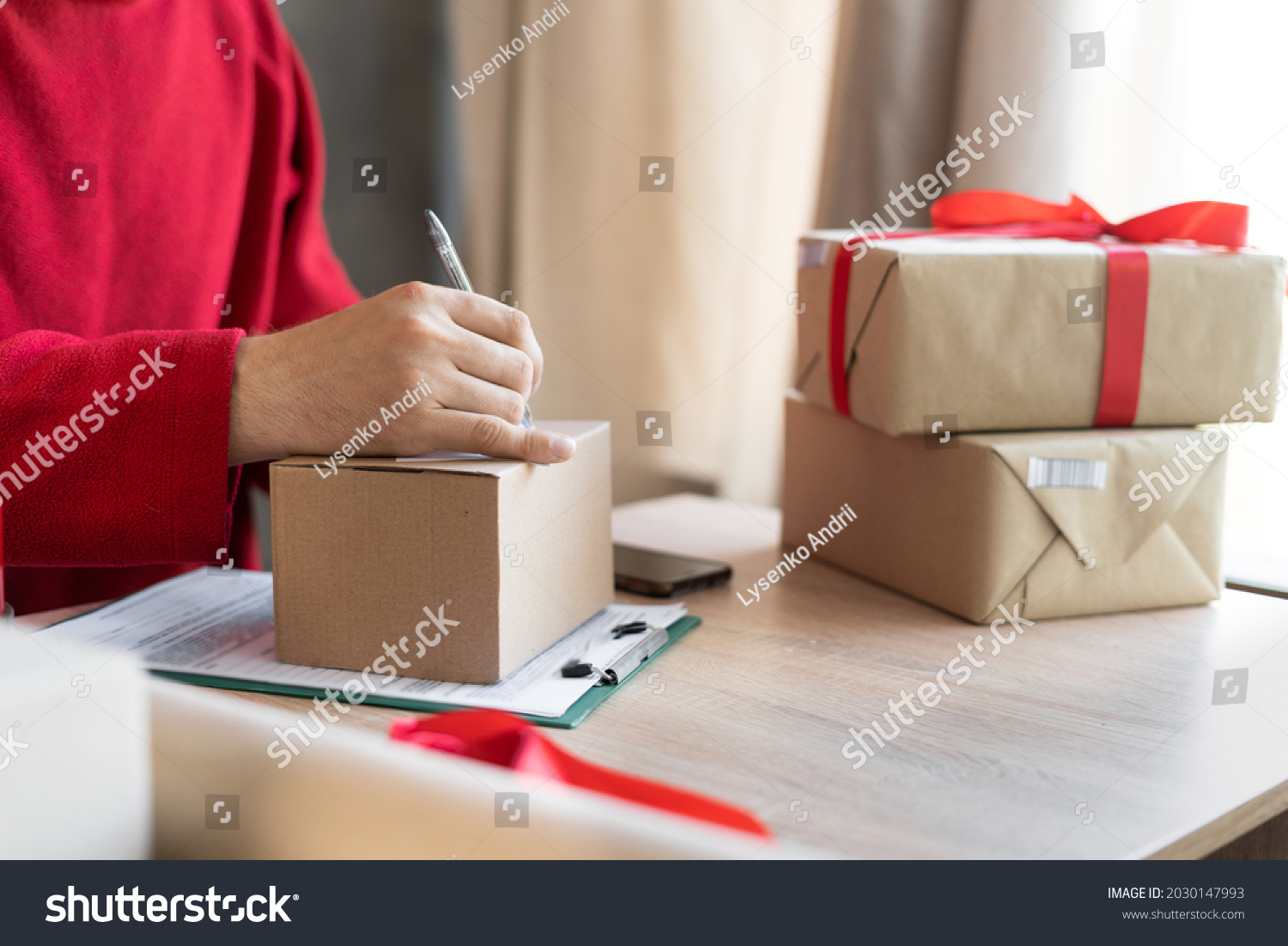close-up of male hands filling out a mailing form on a parcel box in the office or at home. small business owner preparing to send christmas presents. postal delivery and people. shipment concept.