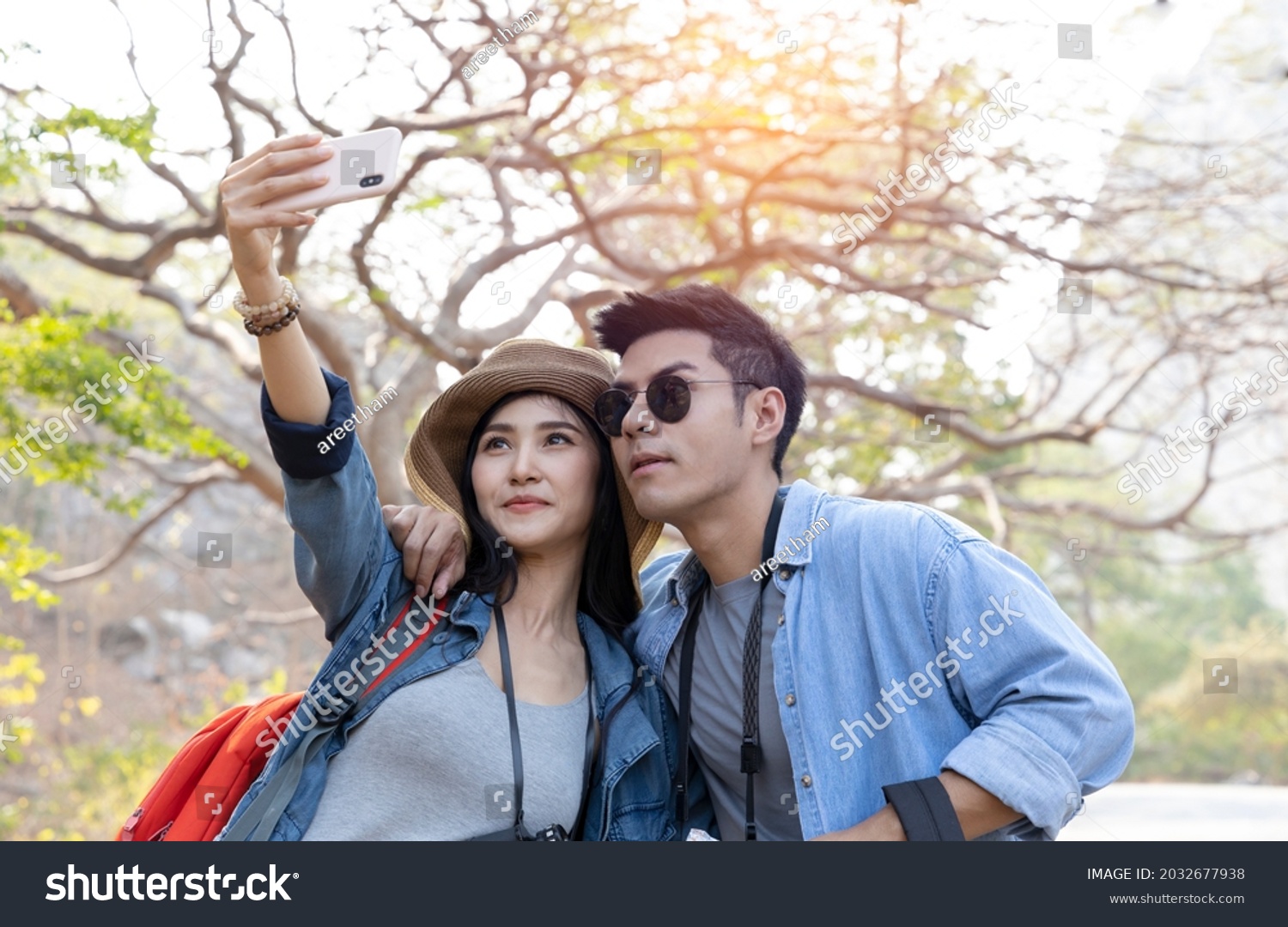 Asian couple taking selfie with smartphone while trekking in national park