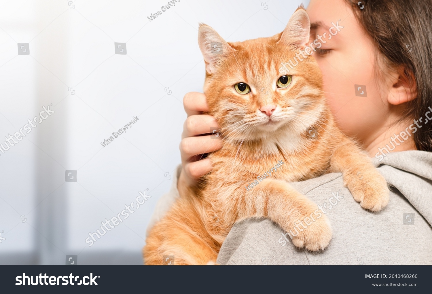 woman holding a ginger cat in her arms