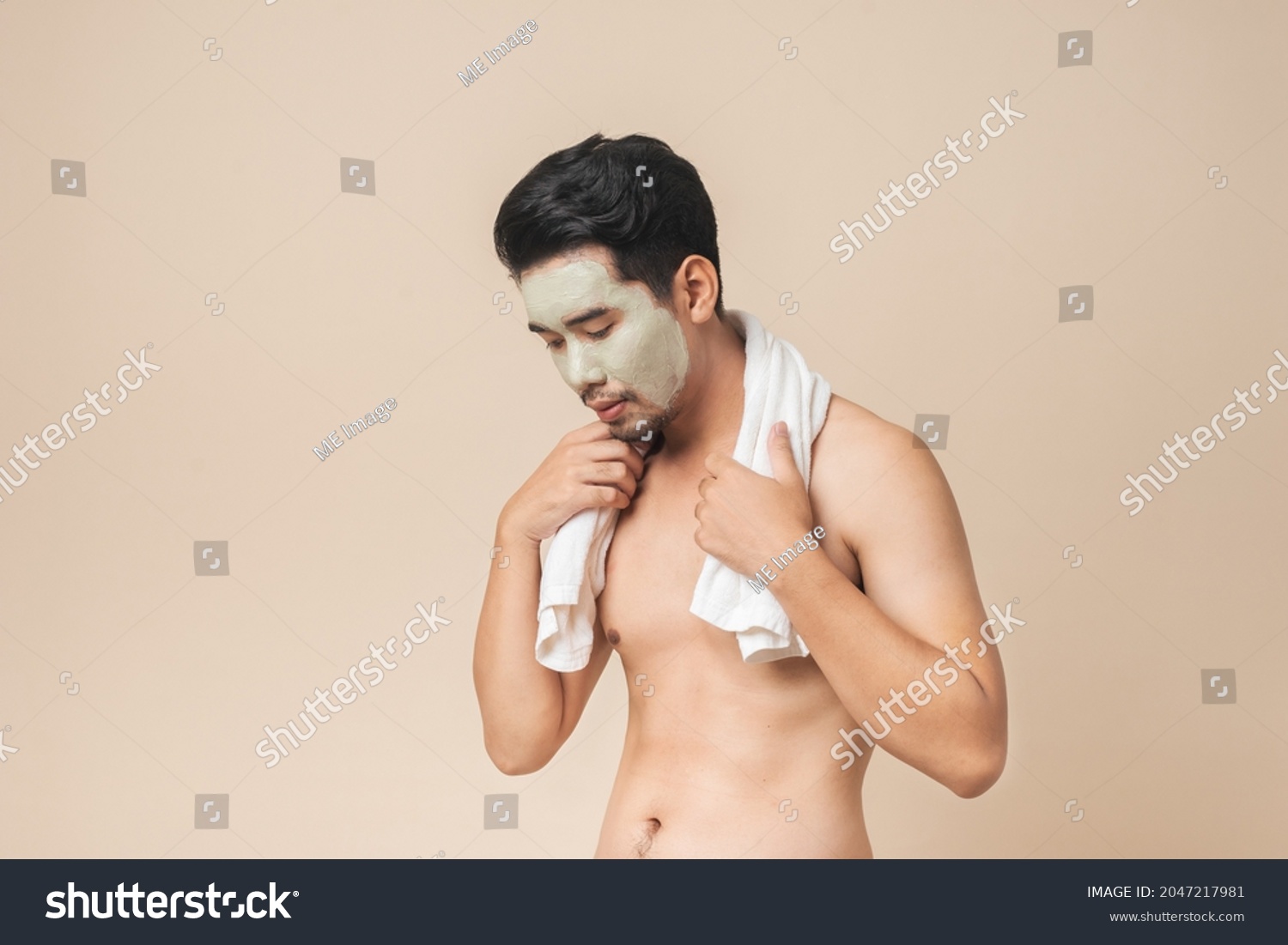 Beside of Asian man healthcare has clay mask on face for facial treatment and skin rejuvenation in studio on brown color background. Concept skin care and facial for men.