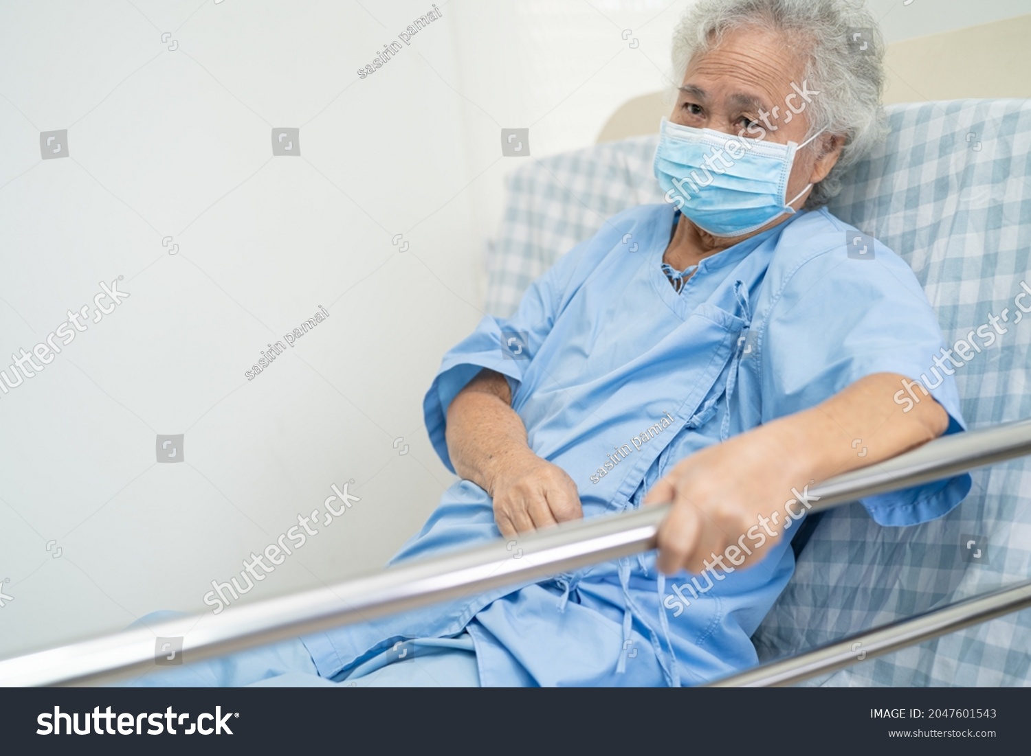 Asian senior or elderly old woman patient lie down handle the rail bed with hope on a bed in the hospital.