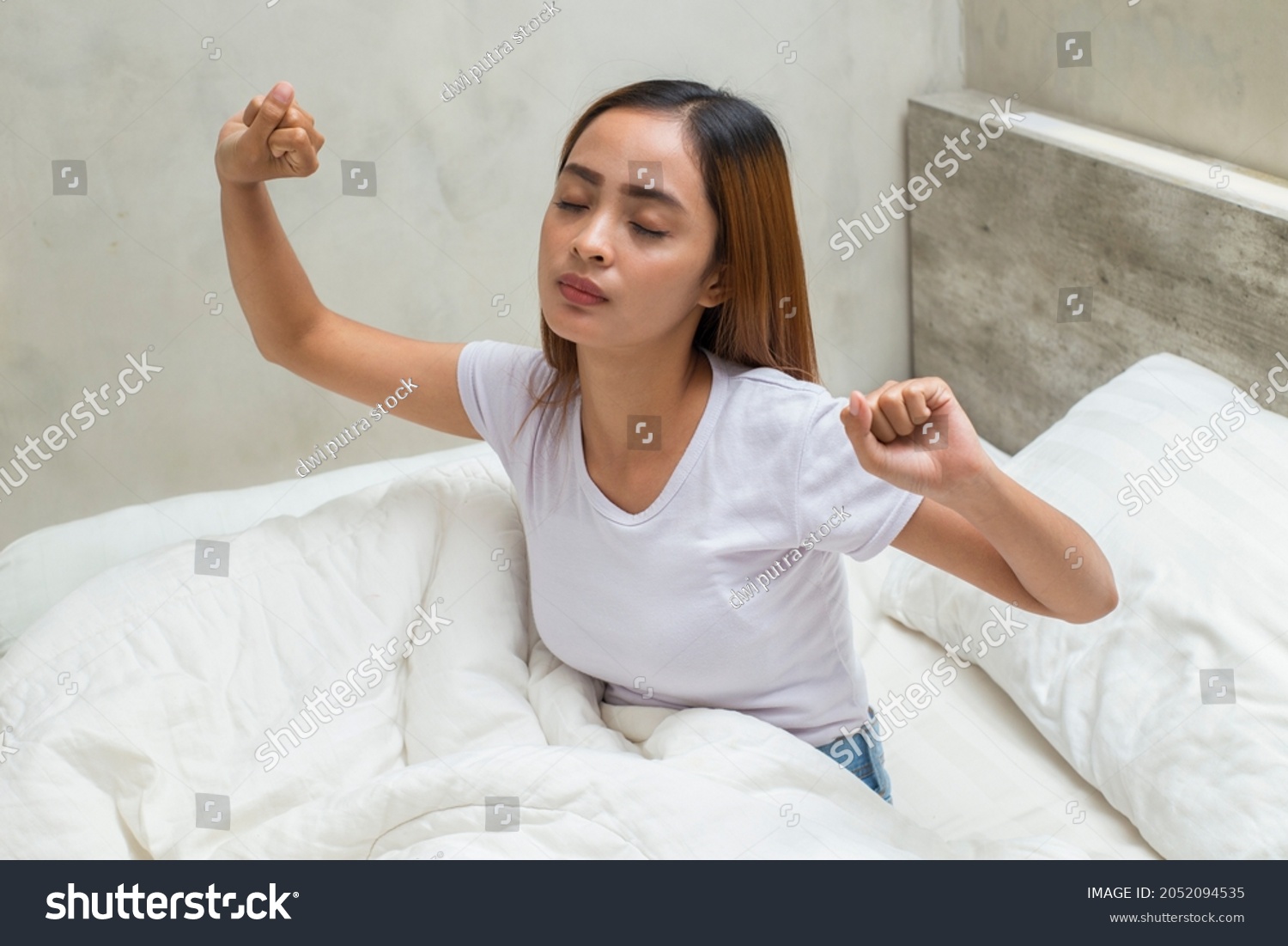 Young asian beautiful woman stretching happy and relaxed after wake up feel fresh at home