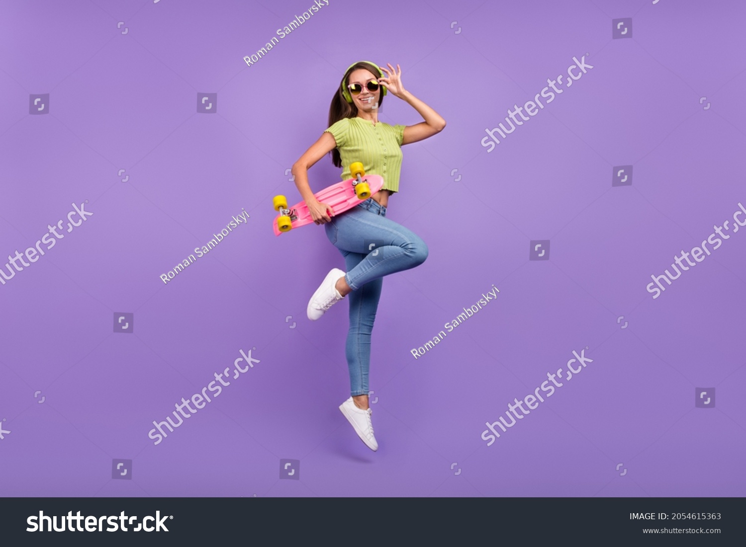 Full length body size view of nice cheerful girl jumping listening pop dancing with skate isolated over purple violet color background