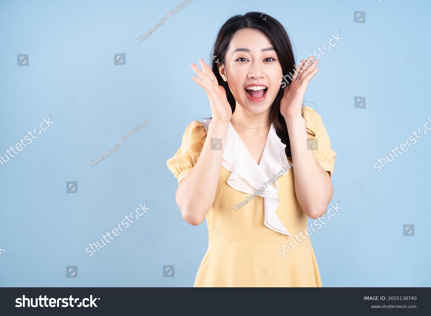 Beautiful Asian young woman wearing yellow dress on blue blackground