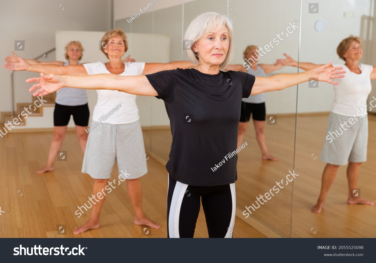 sporty mature woman practicing hatha yoga with group of females
