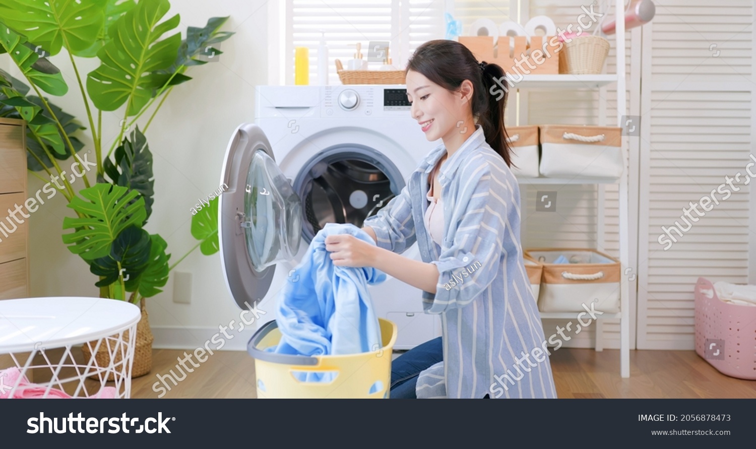 Asian housewife put clothes into washing machine happily at home