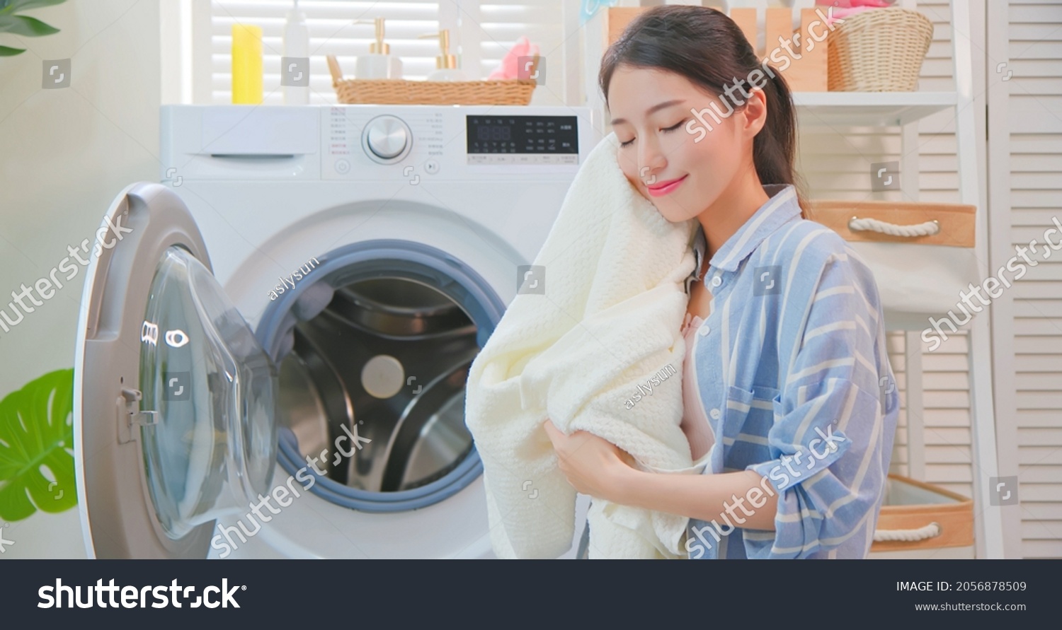 Asian housewife take clothes from washing machine happily at home