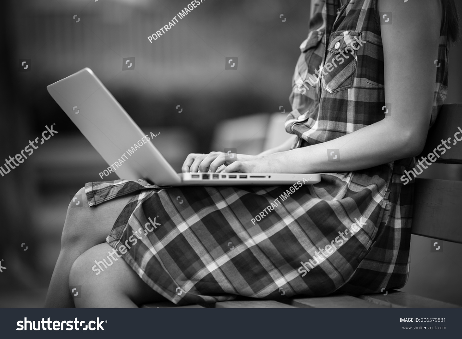 Beautiful young woman using laptop in park