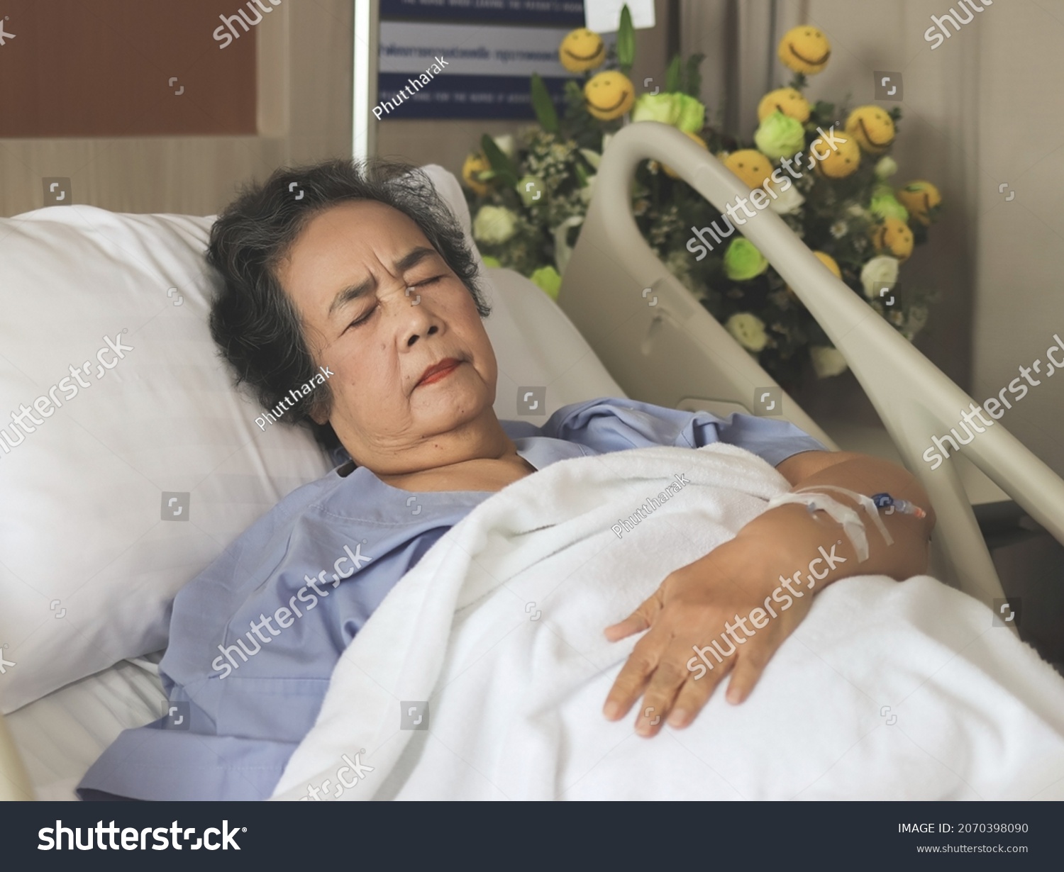 Portrait of lonely Asian senior woman lying in hospital bed feeling pain. Elderly health concept.