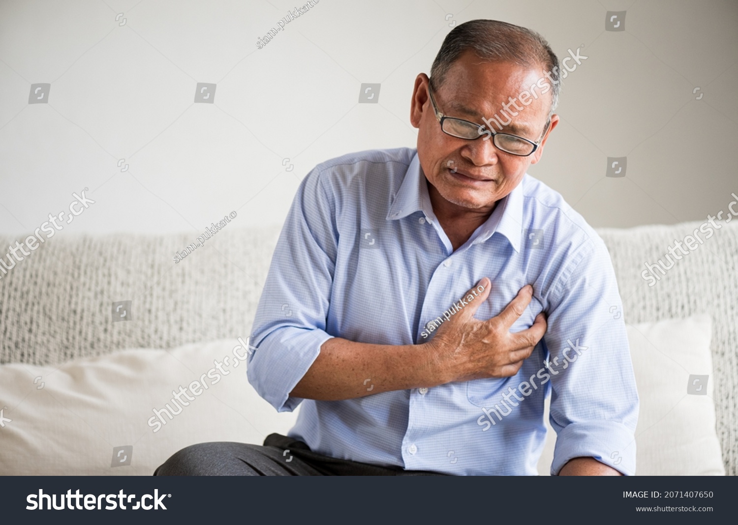 Close Up senior male asian suffering from bad pain in his chest heart attack at home. Healthcare and medical concept of senior heart disease.