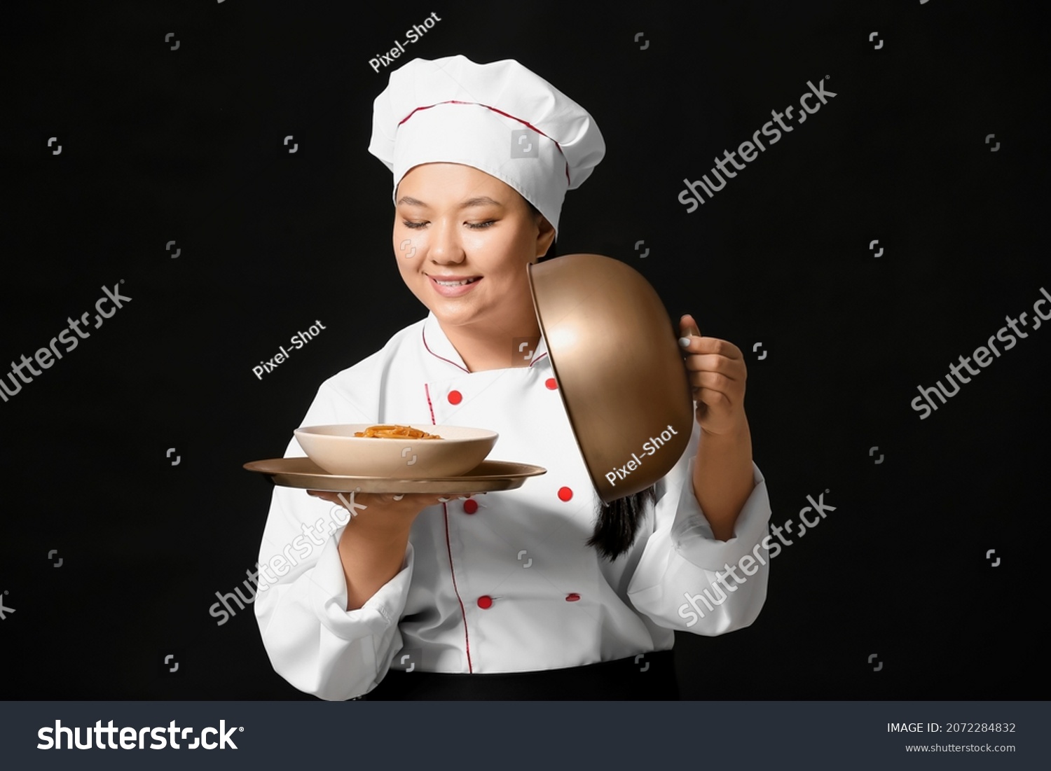 Beautiful Asian chef with dish on dark background