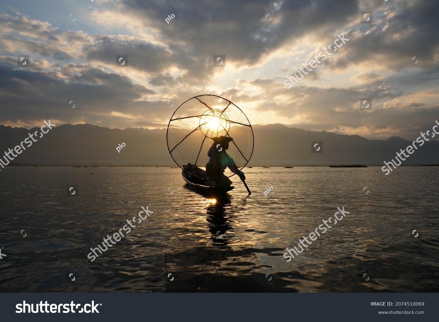 silhouette of local fisherman using coop to catching in inle lake at sunrise