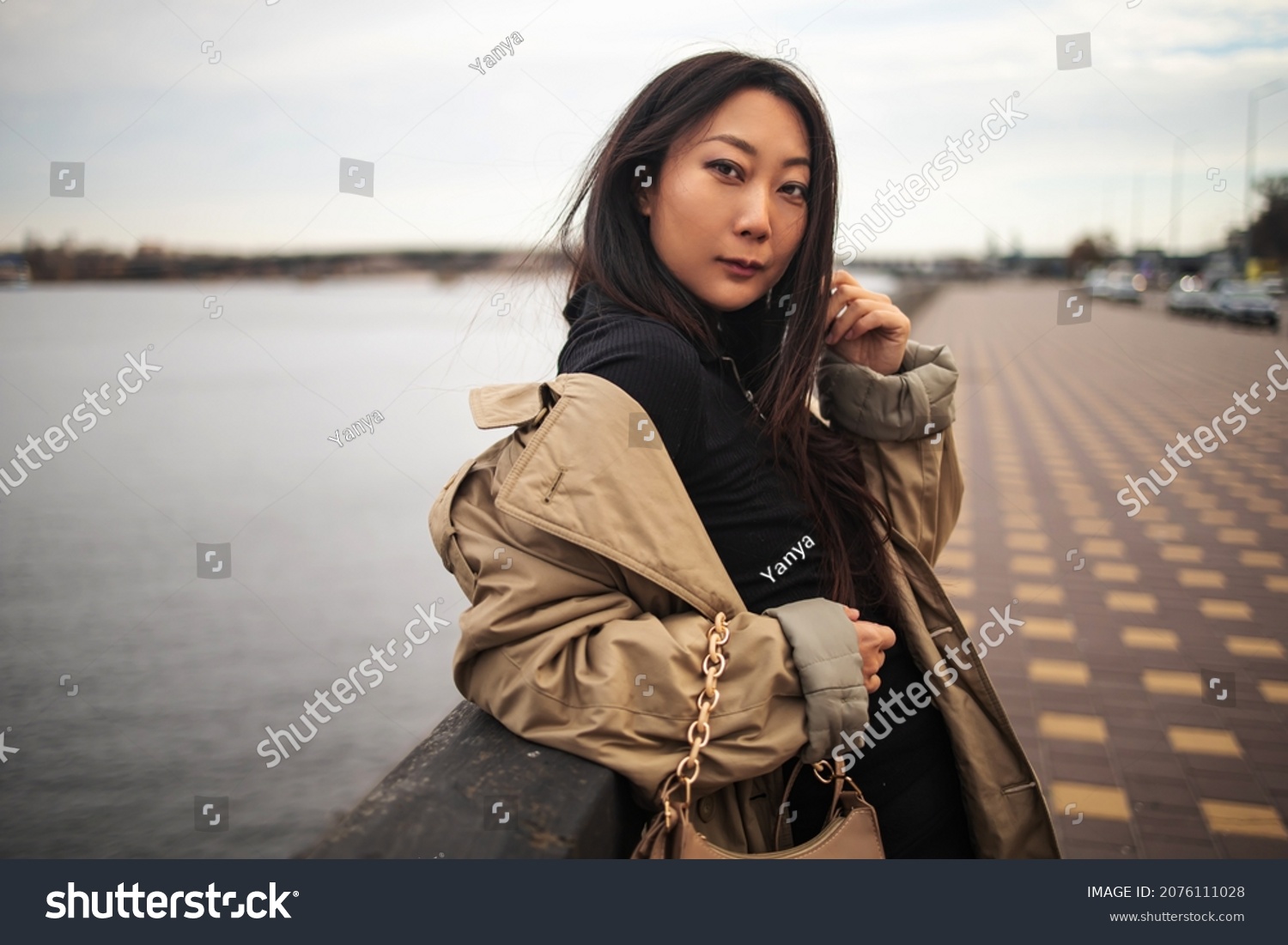 Pretty young asian woman lifestyle with winter clothing along a seawall on the bay with a downtown skyline.