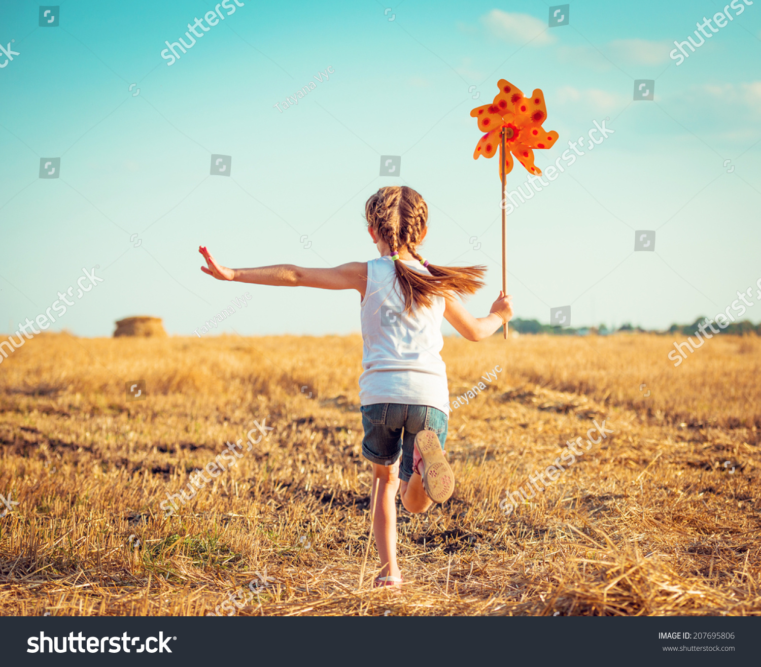 cute little girl in summer day holds windmill in hand
