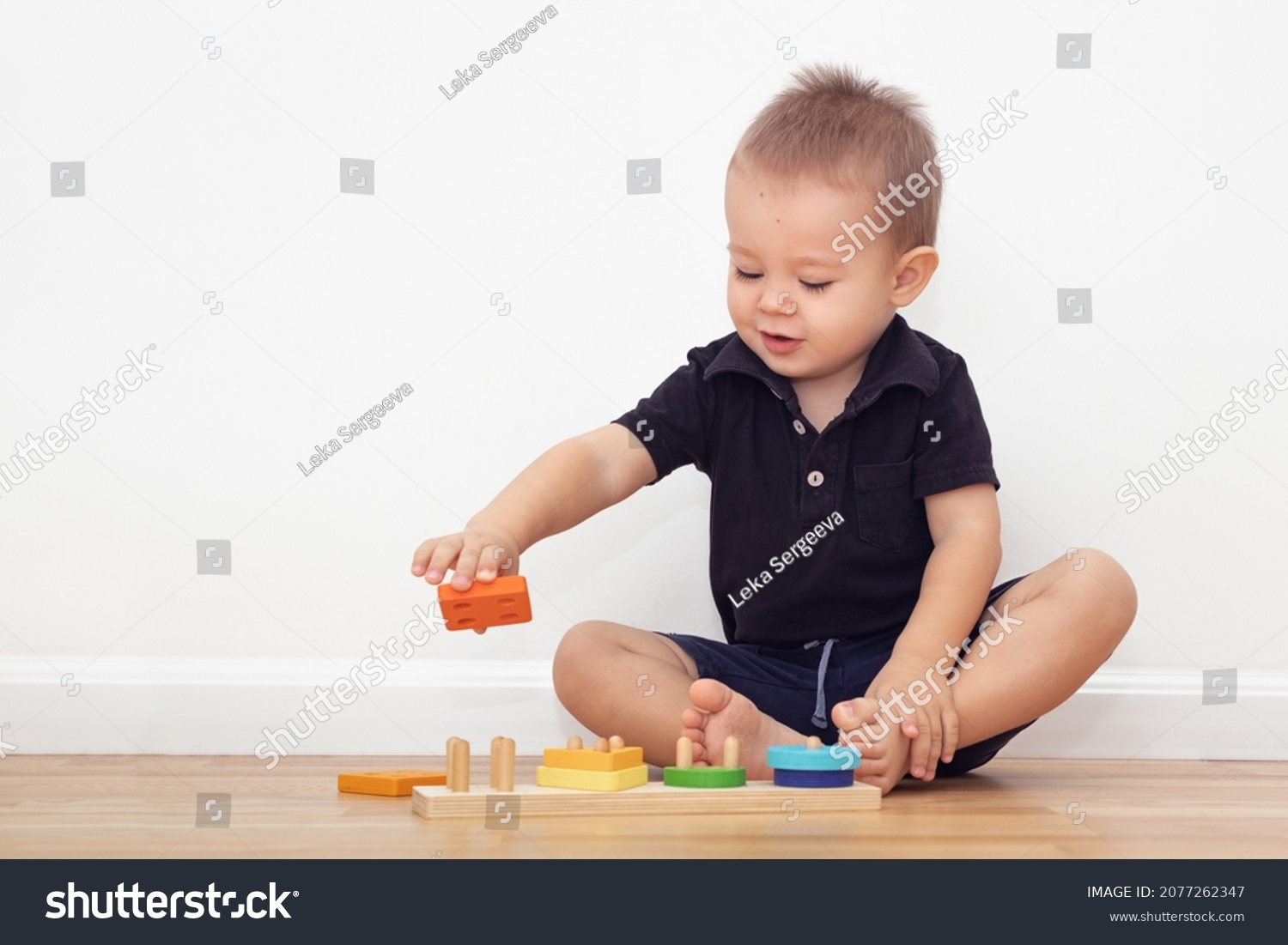 2 year old boy sitting at home on the floor and playing with blocks_站酷海