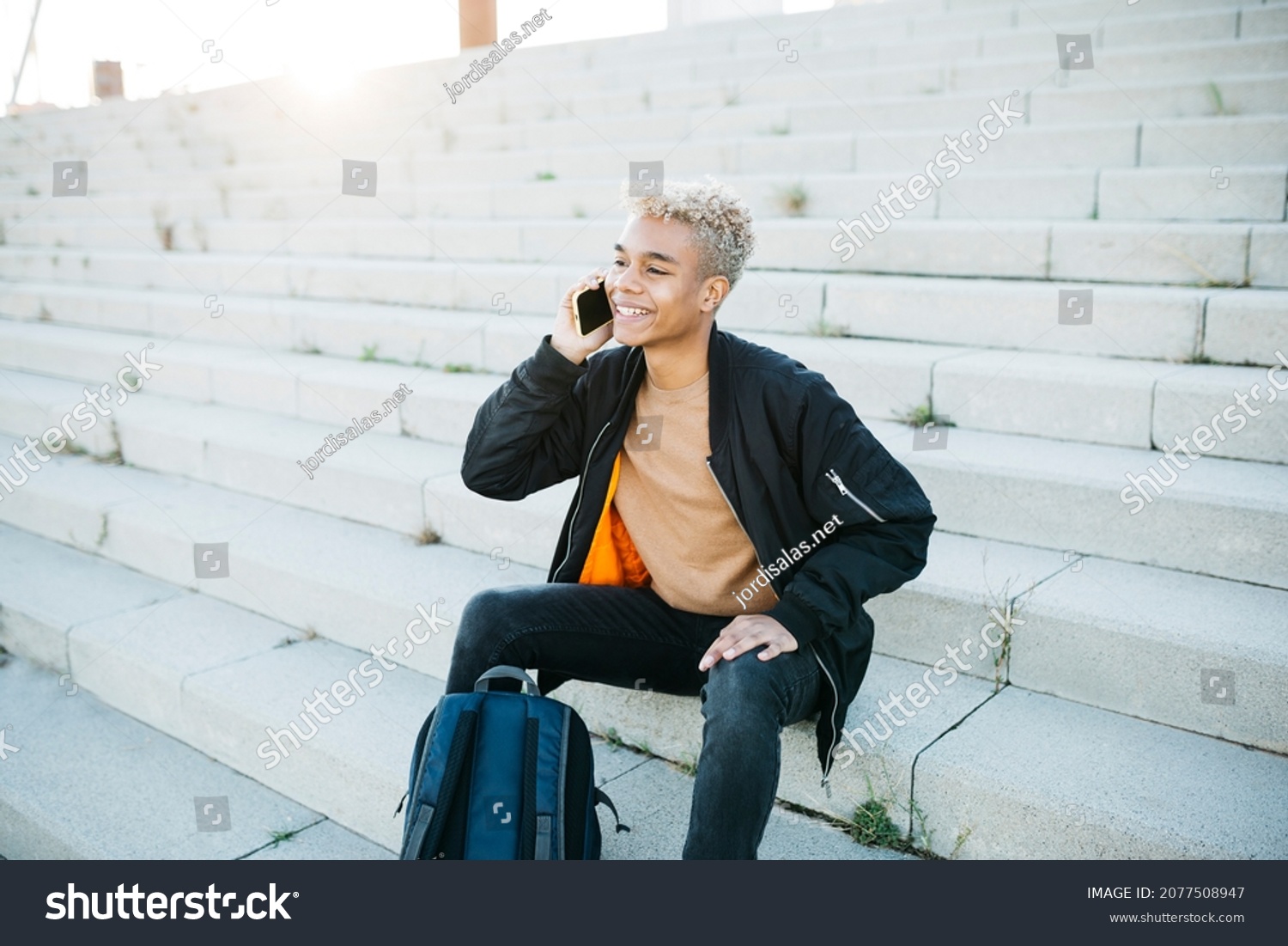 Young latin american male sitting on stairs and having a conversation ...