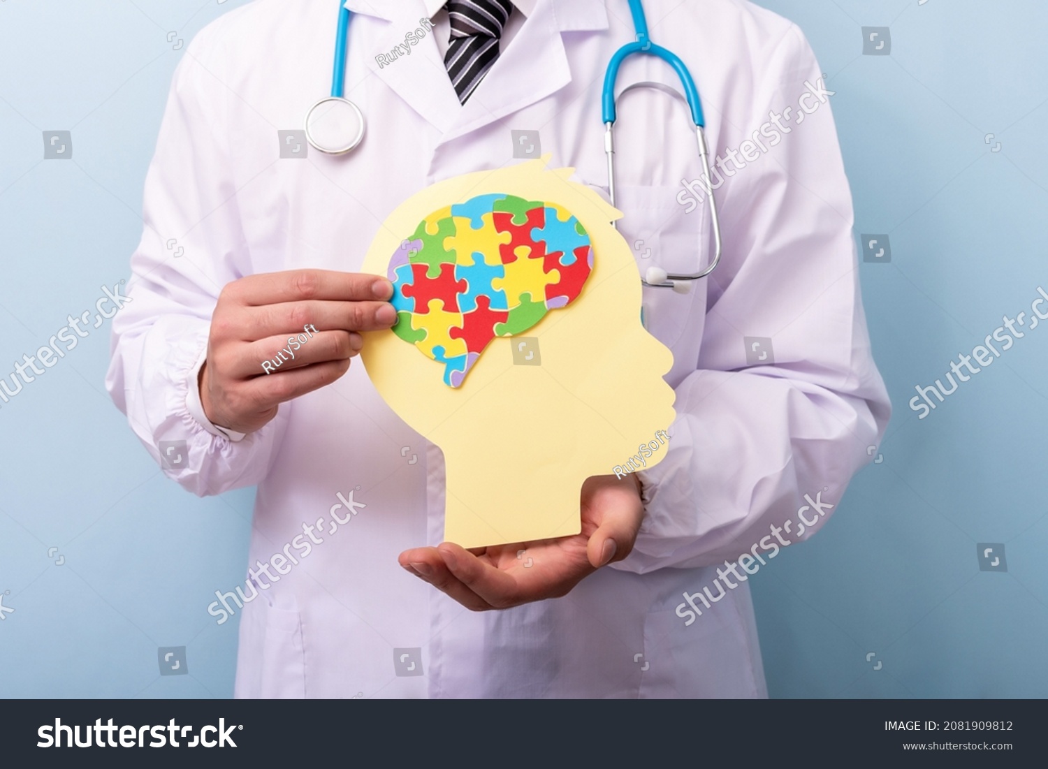 Doctor hands holding head with jigsaw puzzle brain shape. Autism spectrum disorder concept. World Autism Awareness Day.