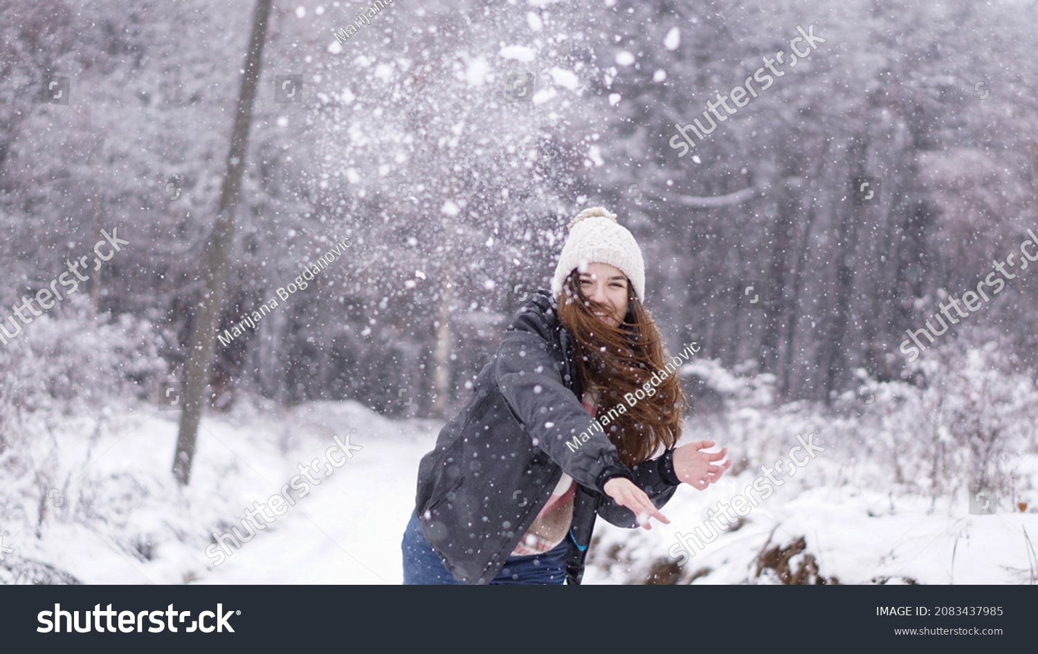 Happy young woman in a snowball fight. Winter holiday spirit. 