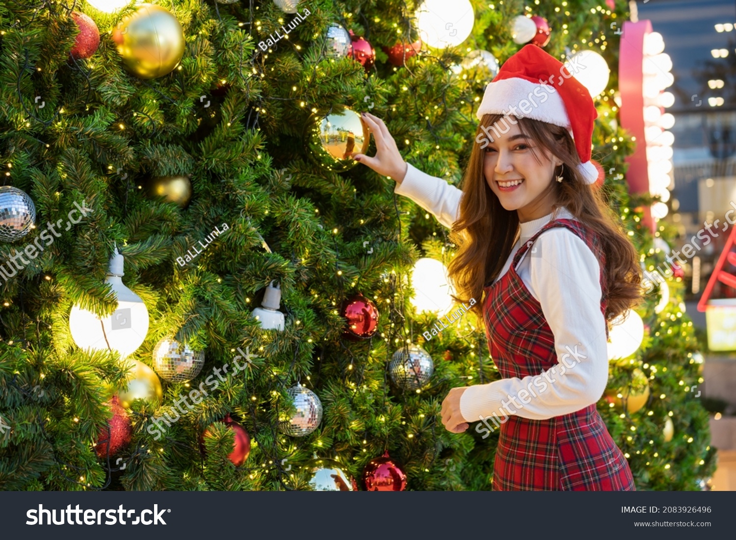happy woman in santa cap decorating Christmas tree  x-mas celebrating
