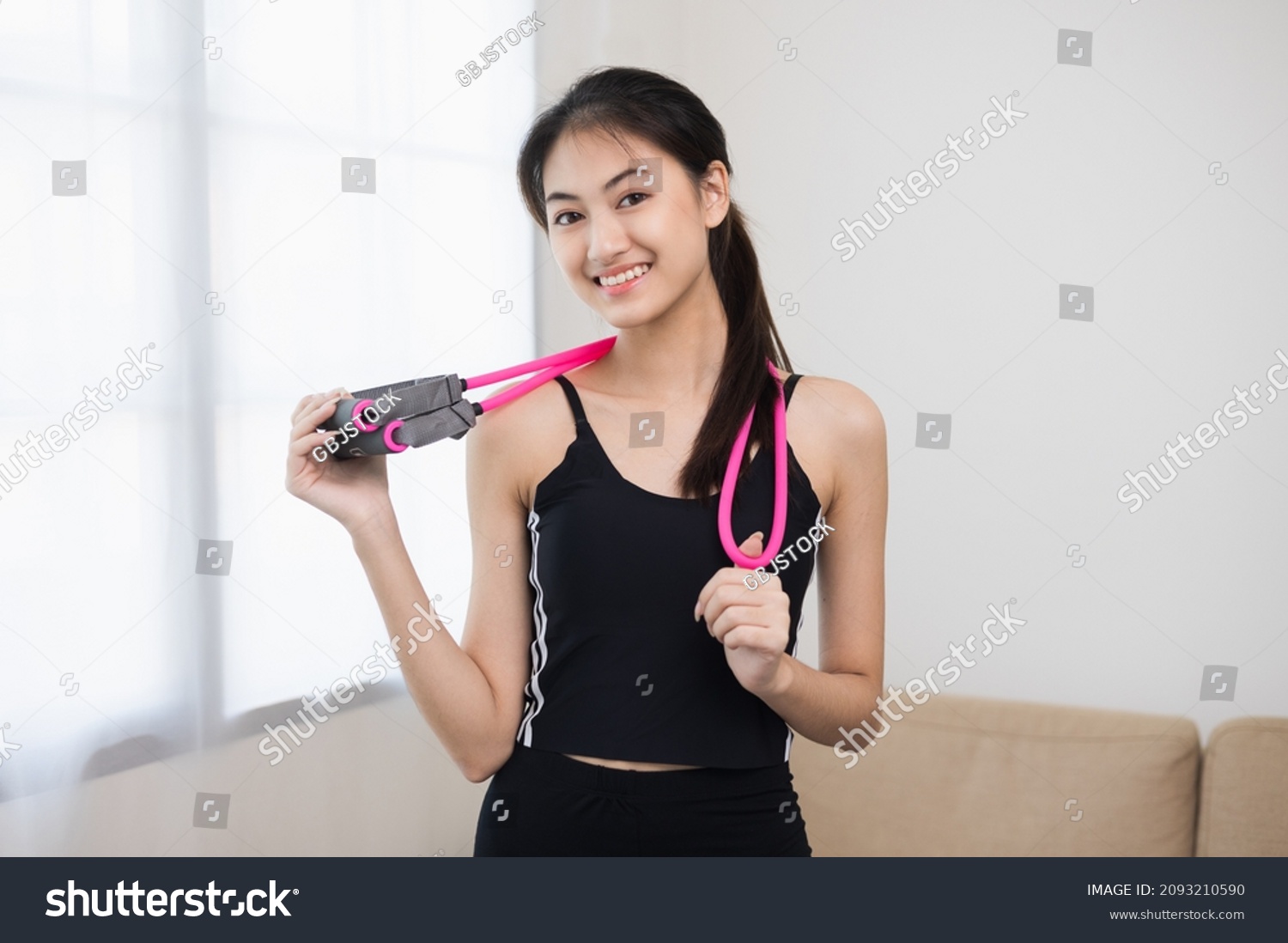 Young beautiful asian woman standing pose smiling to camera. Cheerfully sporty female workout and exercise wearing sport wear at home. Charming woman fitness training and stretching in living room