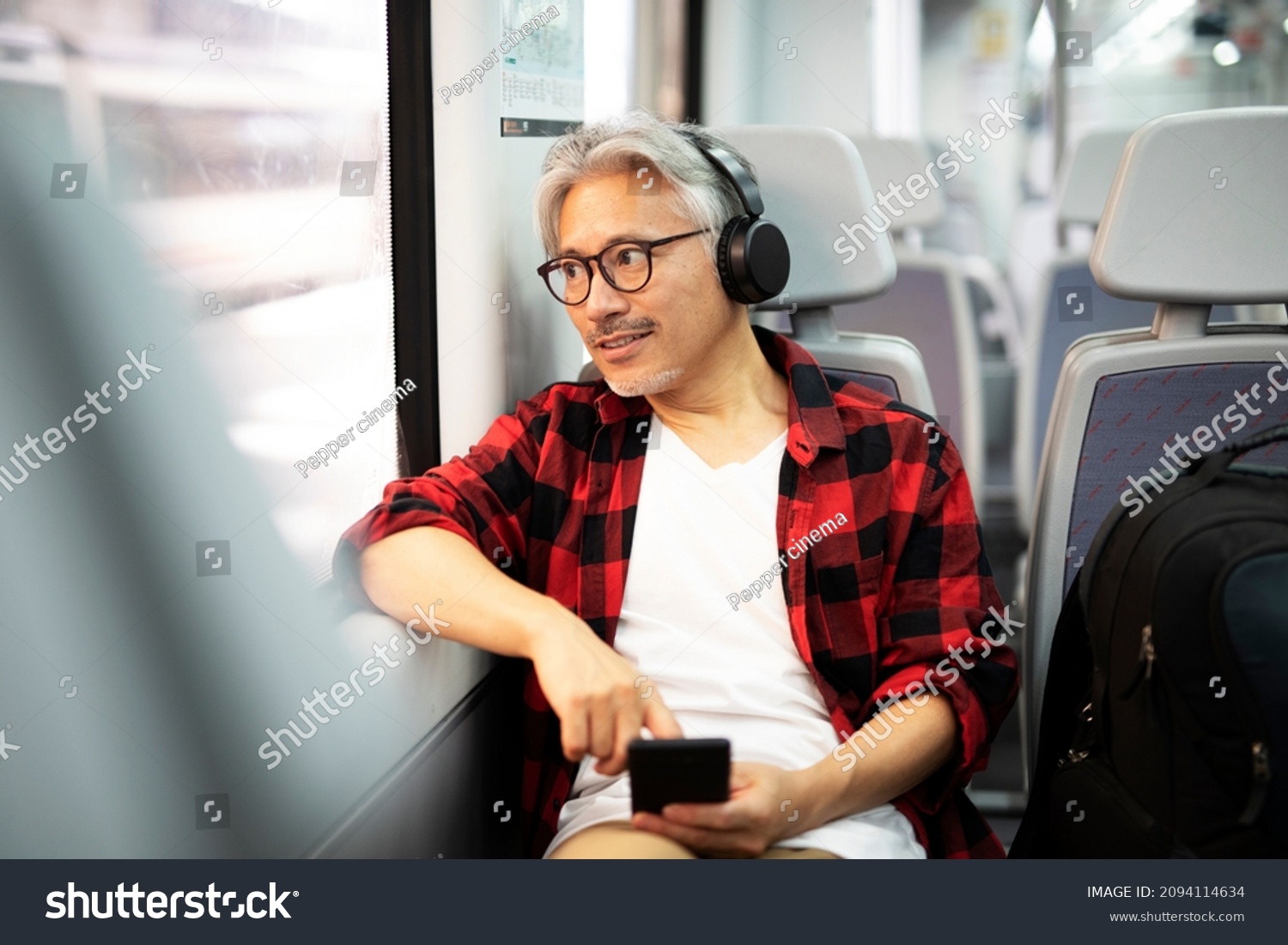 Senior man traveling by train. Man listening the music while enjoying in travel	
