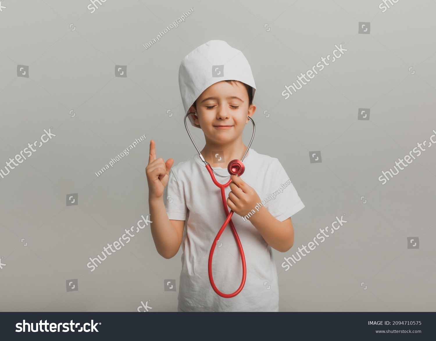 boy in a doctor's cap holds a stethoscope on a light background. little doctor. high quality studio photo