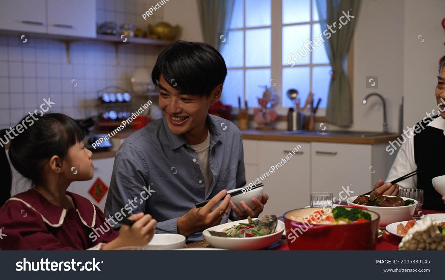 happy chinese father talking to his daughter while enjoying big meal with family. mixed generation having Chinese new year dinner at home.