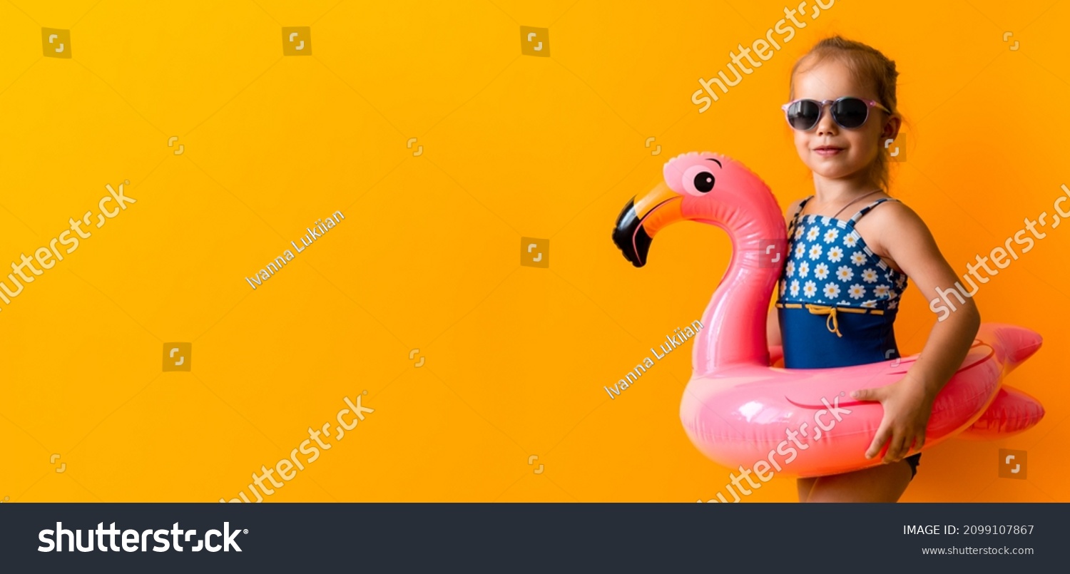 banner happy little child swimmer sport baby girl wear sun glasses swimsuit Kid Inflatable swimming ring Pink Flamingo isolated orange background hot summer vacation hobby concept. Copy Space