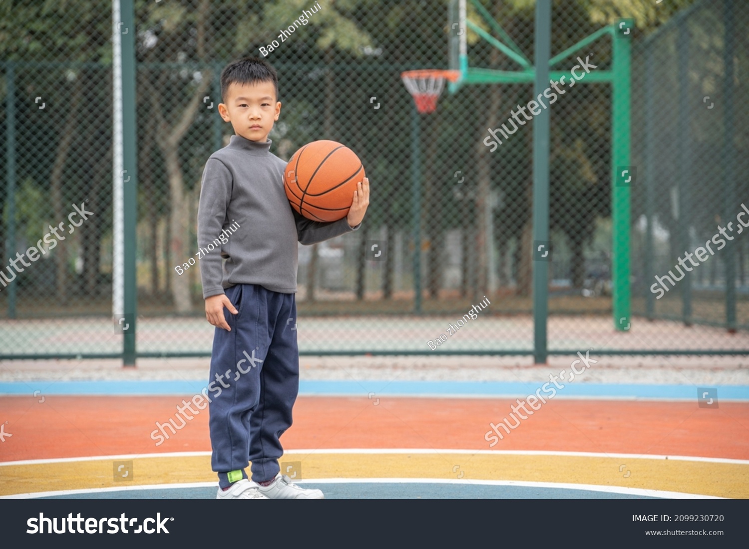 A teenager holding a basketball on the court