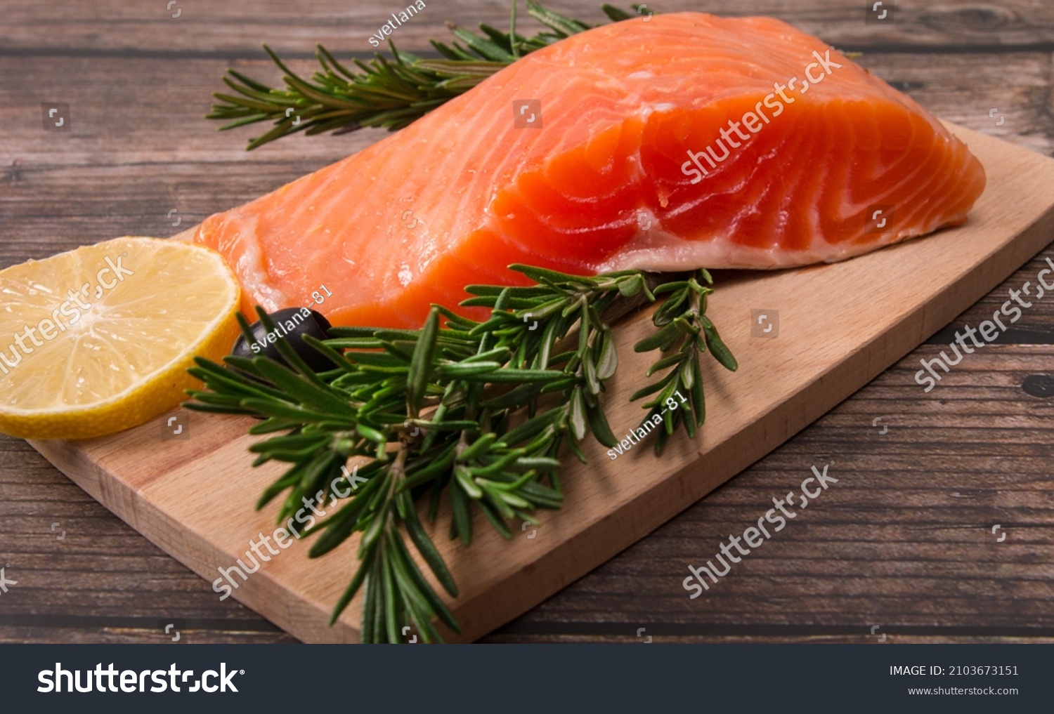 red salted fish on a cutting board with rosemary and lemon